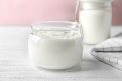 Photo of Glass jar tasty with yogurt on wooden table