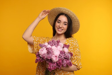 Beautiful woman with bouquet of spring flowers on yellow background