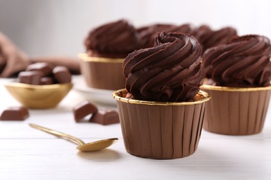 Photo of Delicious chocolate cupcake on white wooden table, closeup