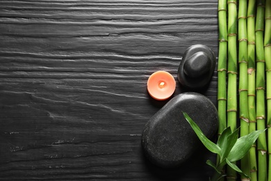 Photo of Flat lay composition with green bamboo stems on black wooden background. Space for text