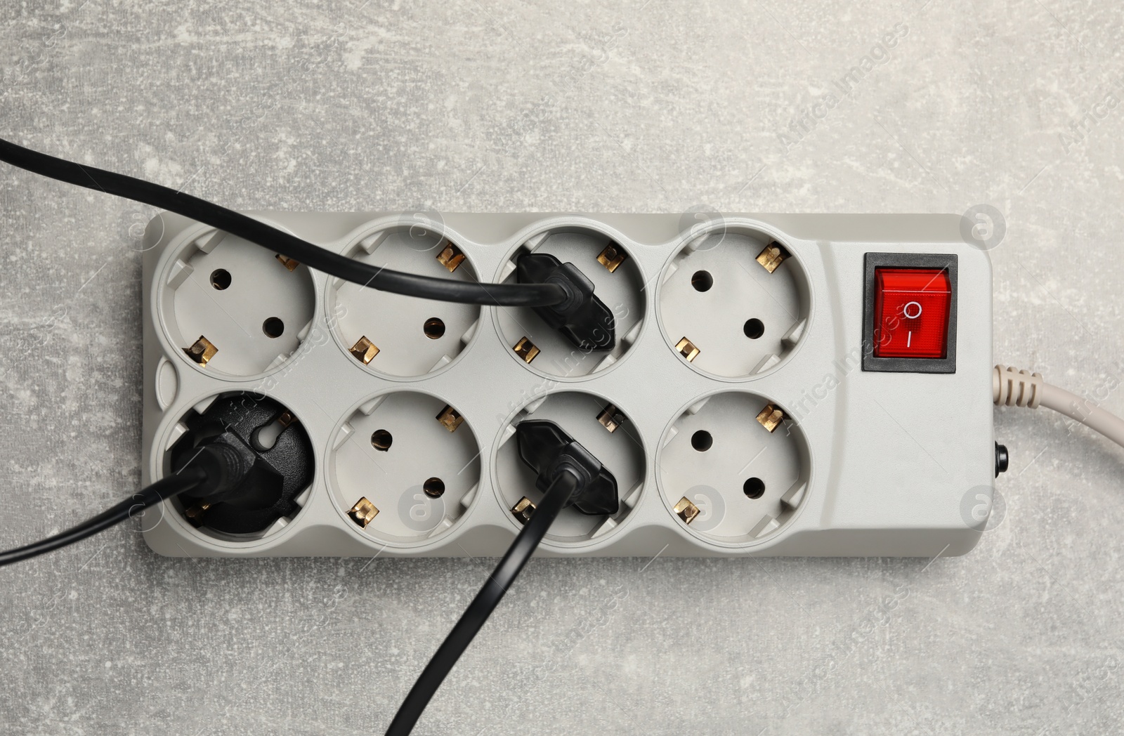 Photo of Power strip with extension cord on light grey table, top view. Electrician's equipment