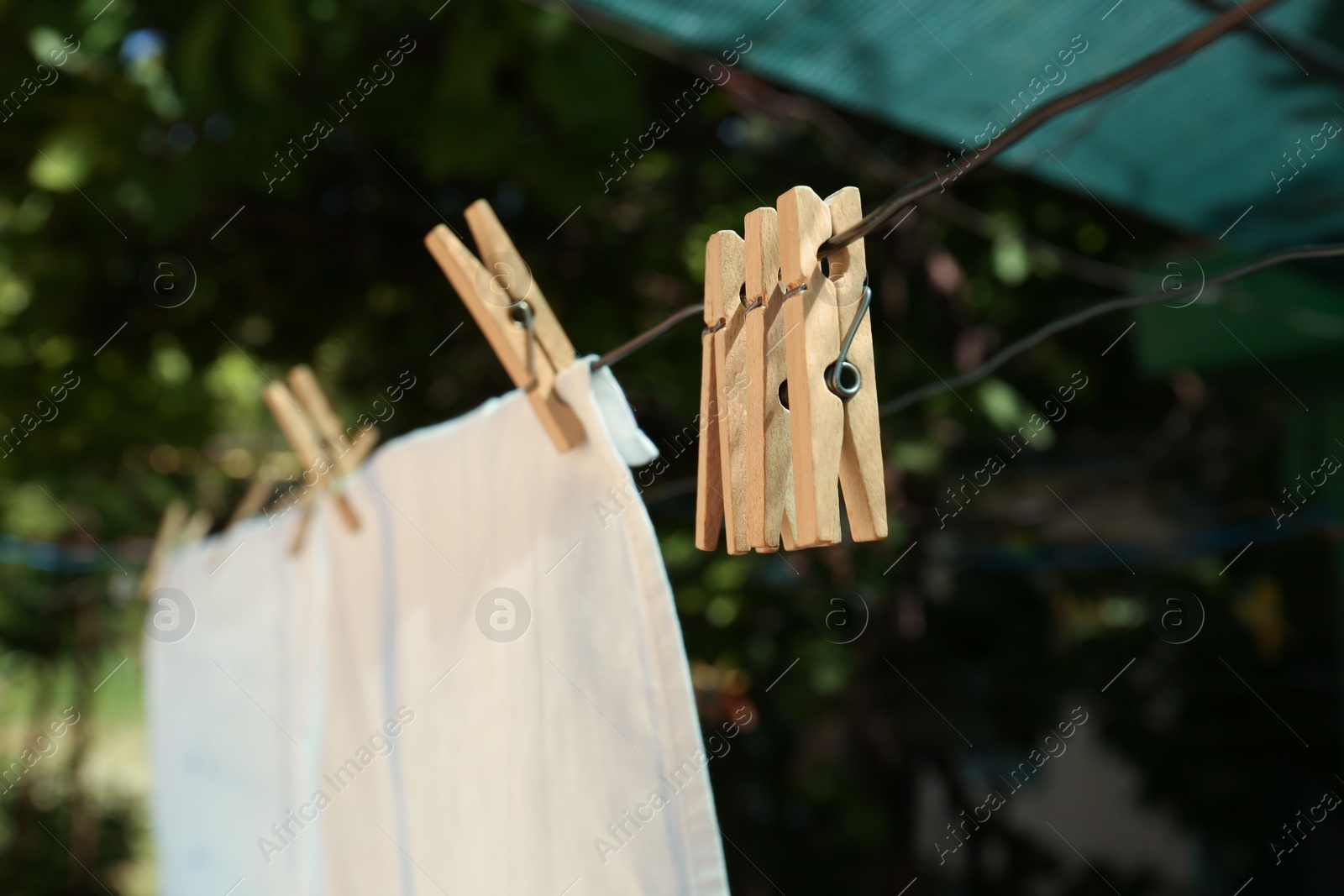 Photo of Washing line with clean laundry and clothespins outdoors, closeup
