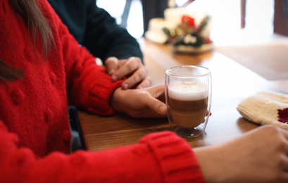 Lovely couple with fresh aromatic coffee at table in cafe, closeup