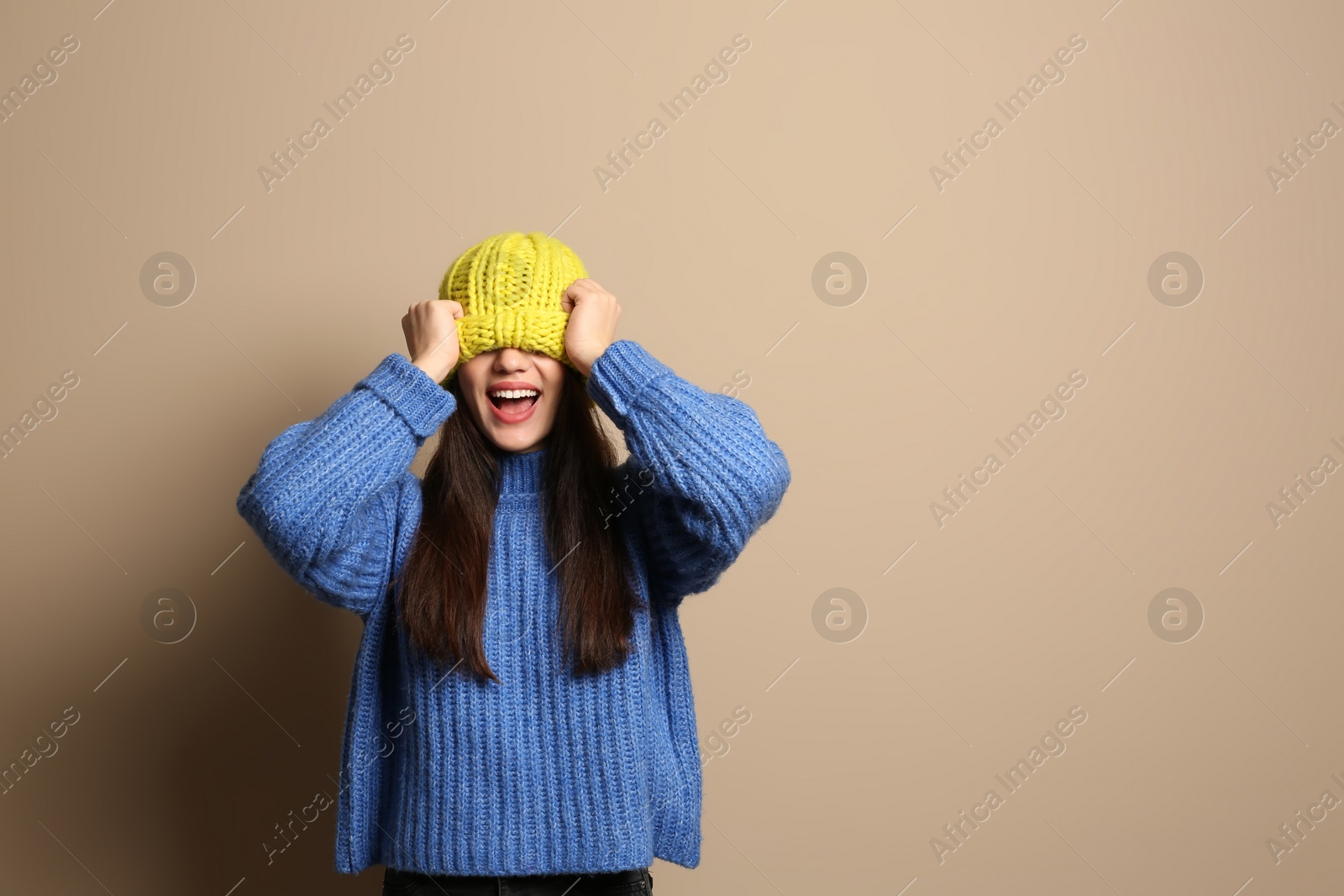 Photo of Young woman wearing warm clothes on color background, space for text. Winter season