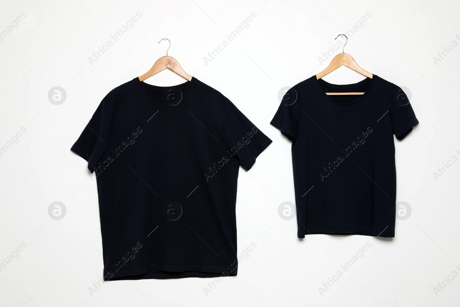 Photo of Hangers with blank t-shirts on white background. Mock up for design