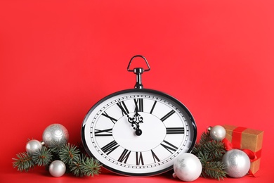 Photo of Clock and festive decor on red background. New Year countdown