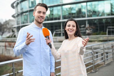 Young journalist interviewing man on city street