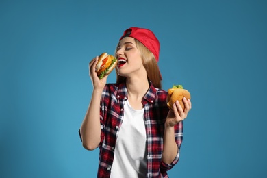 Photo of Pretty woman with tasty burgers on color background