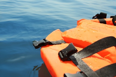 Photo of Orange life jacket floating in sea, closeup. Emergency rescue equipment