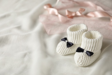 Photo of Handmade baby booties on plaid. Space for text