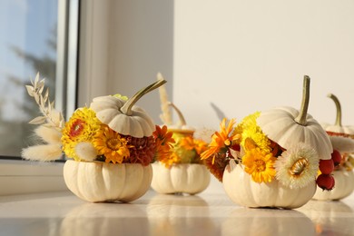 Photo of Composition with small pumpkins, beautiful flowers and spikelets on white window sill indoors, closeup