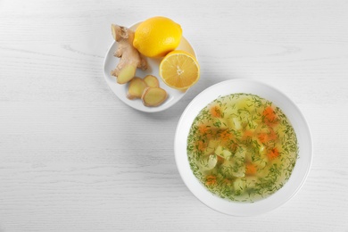 Flat lay composition with bowl of fresh homemade soup to cure flu on wooden background