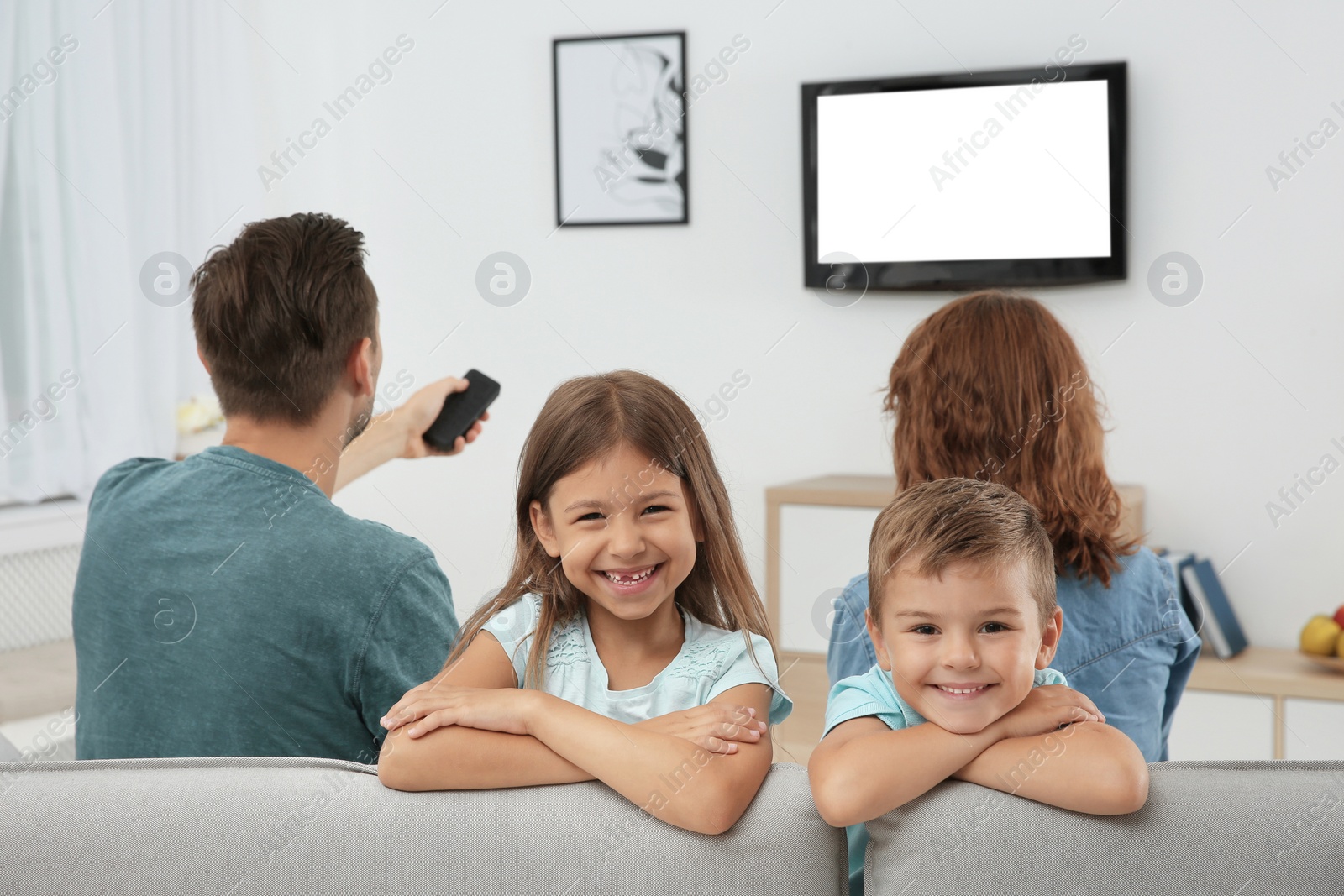 Photo of Family watching TV in room at home