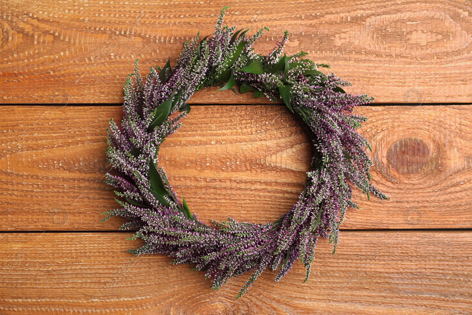 Photo of Beautiful autumnal wreath with heather flowers on wooden background, top view. Space for text