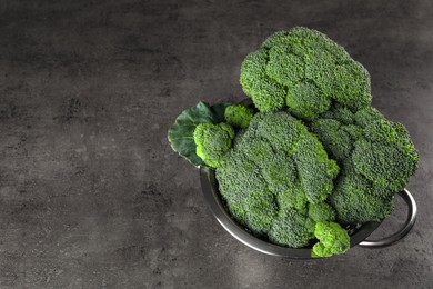 Photo of Colander with fresh raw broccoli on grey table, above view. Space for text