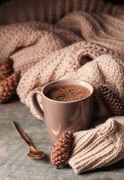 Photo of Composition with cup of hot cozy drink and autumn sweater on table