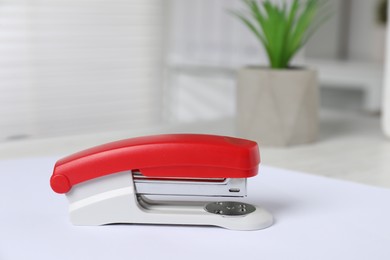 Photo of Bright stapler and paper on table indoors, closeup