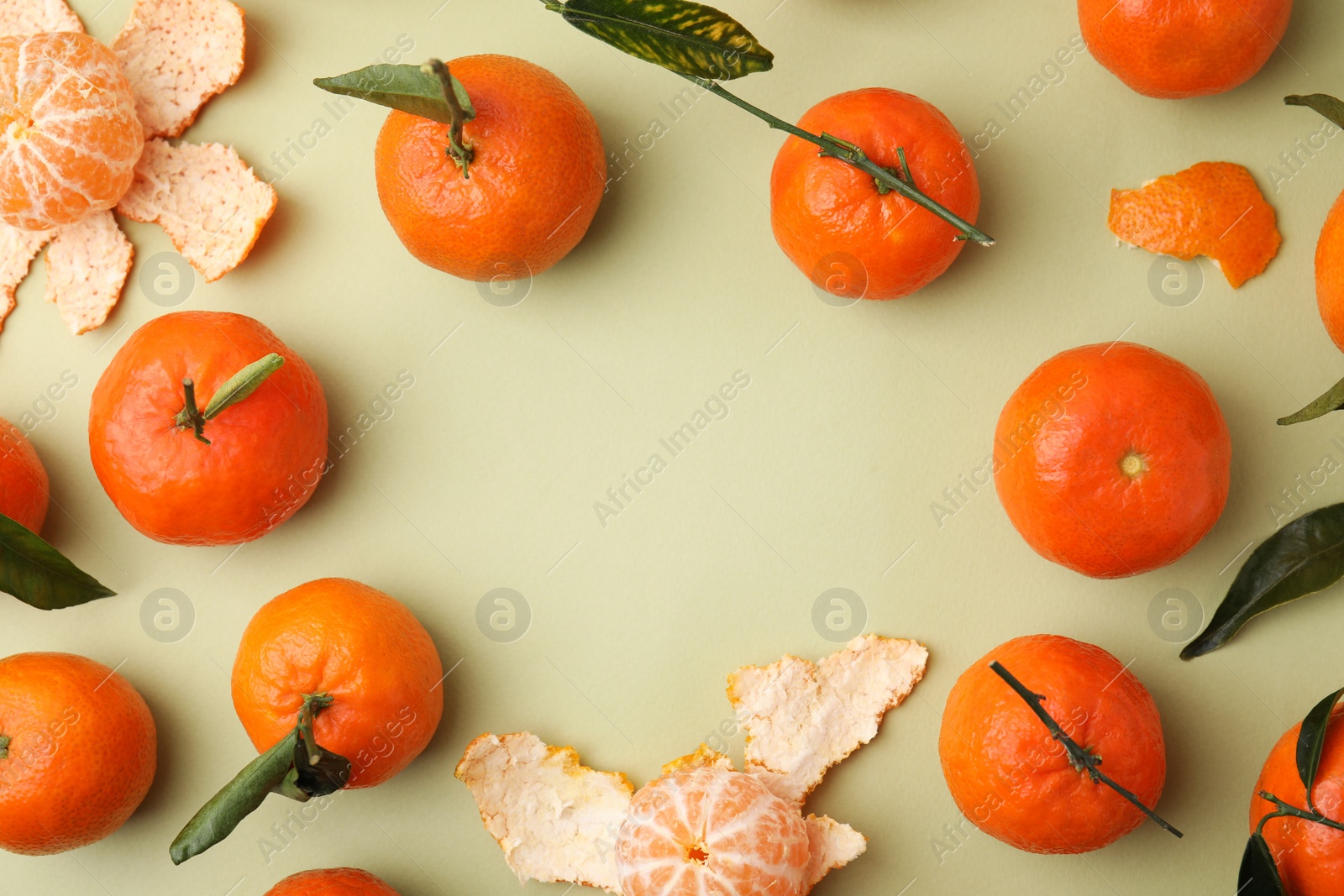 Photo of Frame made of many fresh ripe tangerines and leaves on light green table, flat lay. Space for text