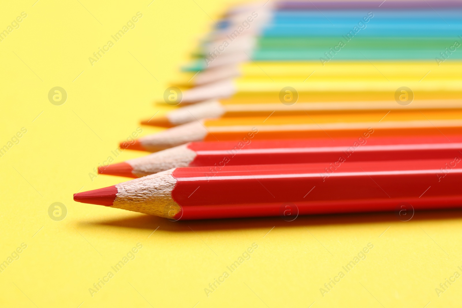 Photo of Different color pencils on yellow background, closeup