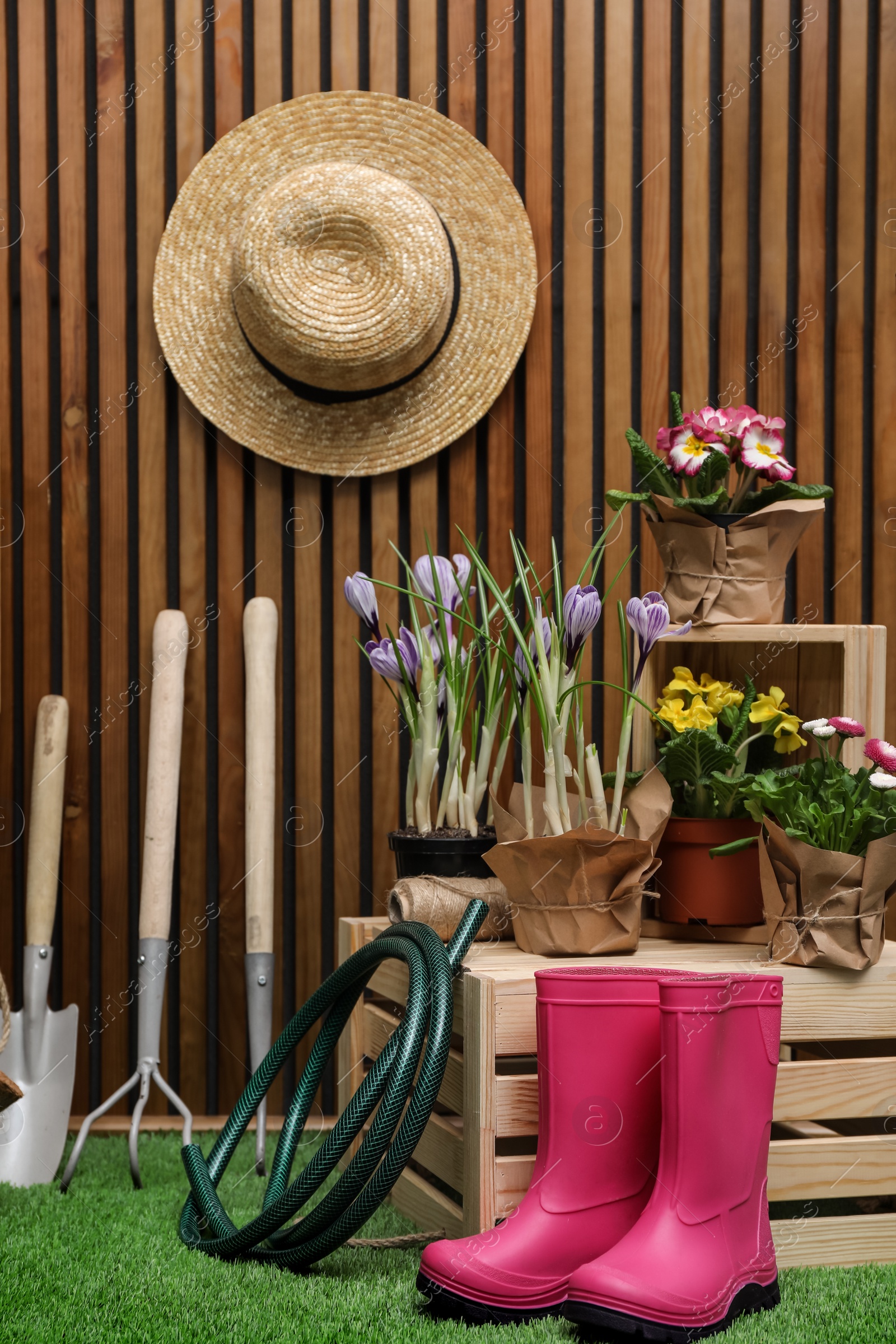 Photo of Composition with different gardening tools on artificial grass at wooden wall