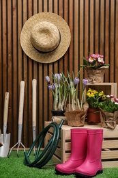 Composition with different gardening tools on artificial grass at wooden wall