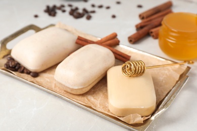 Photo of Different soap bars in tray with parchment paper on light background
