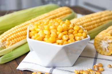 Photo of Bowl with corn kernels on wooden table