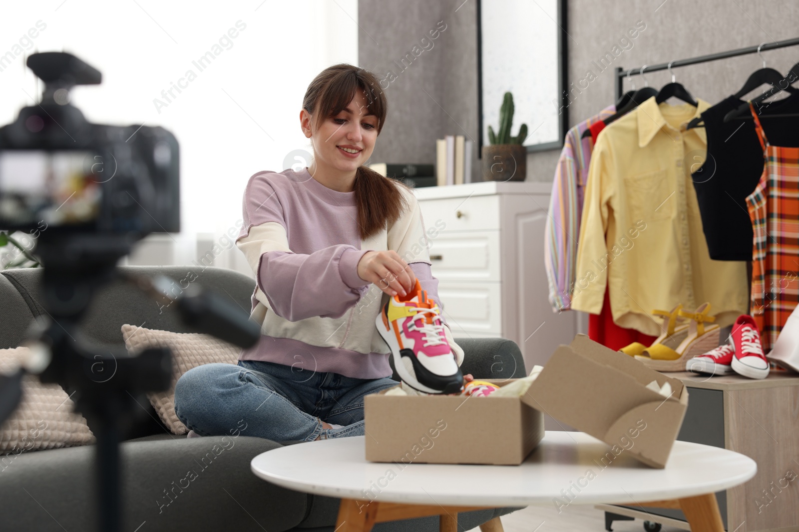 Photo of Smiling fashion blogger showing her shoes while recording video at home