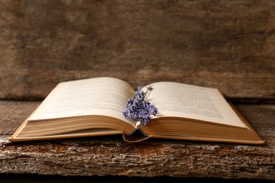 Photo of Open book with beautiful dried flowers on wooden table
