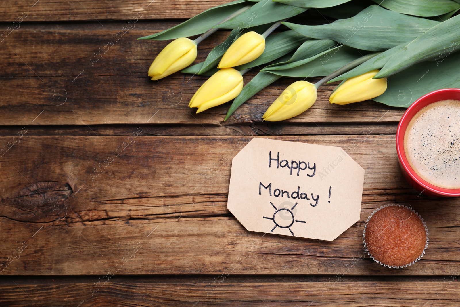 Photo of Happy Monday message, aromatic coffee, cupcake and tulips on wooden table, flat lay. Space for text