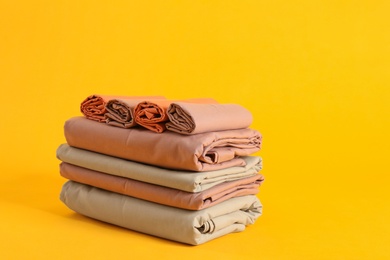 Photo of Stack of clean bed sheets on yellow background