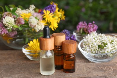 Photo of Bottles of essential oils and many beautiful flowers on wooden table