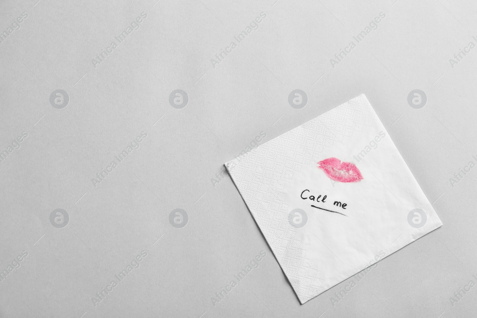 Photo of Paper napkin with lipstick mark and words CALL ME on grey background, top view. Space for text