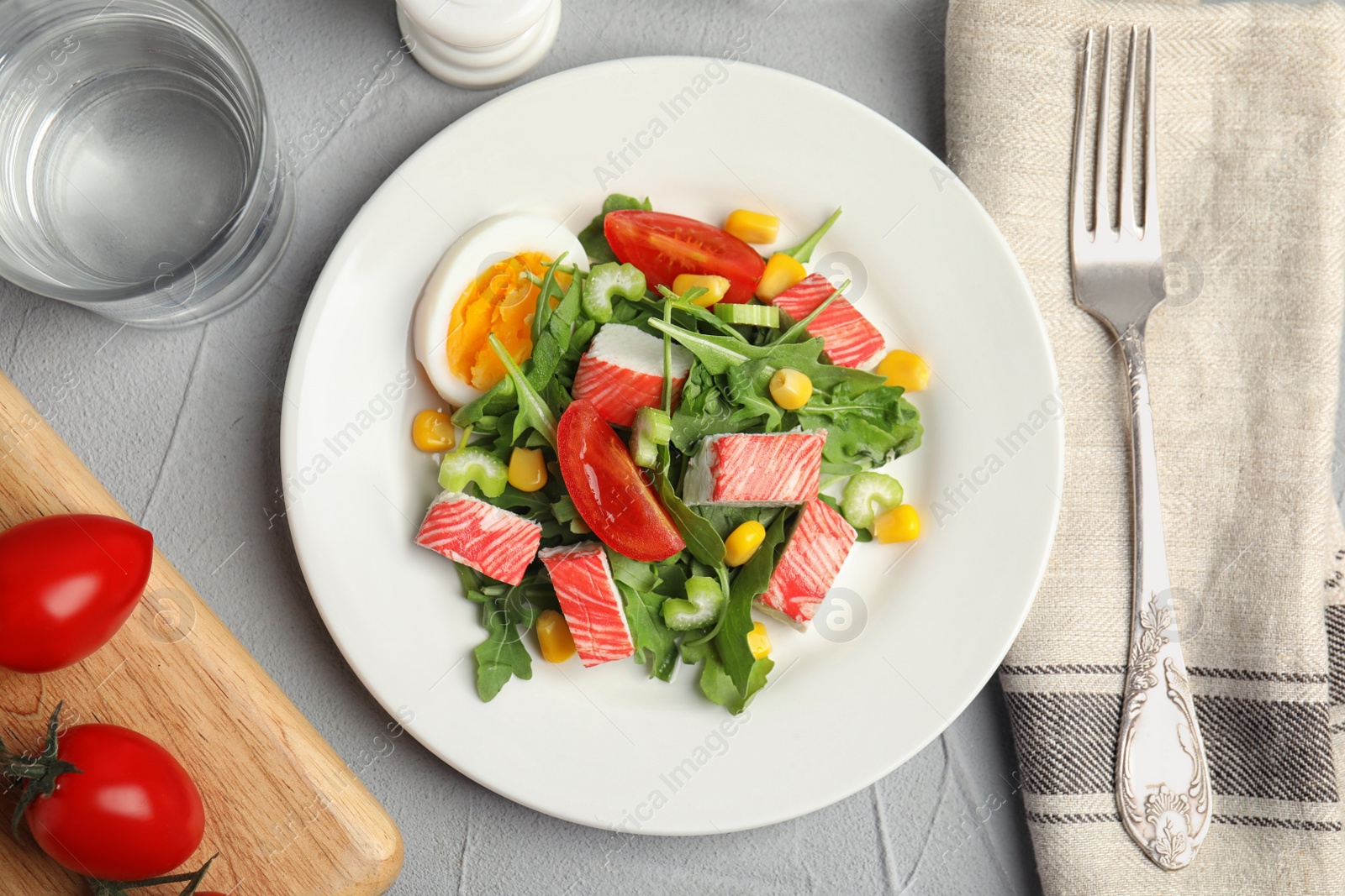 Photo of Delicious crab stick salad served on grey table, flat lay