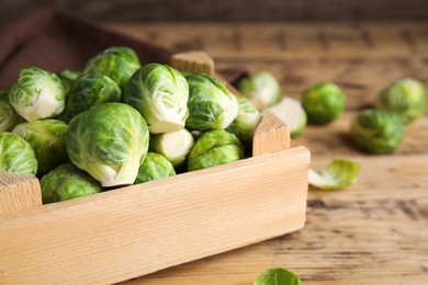 Photo of Crate with fresh Brussels sprouts on wooden table, closeup