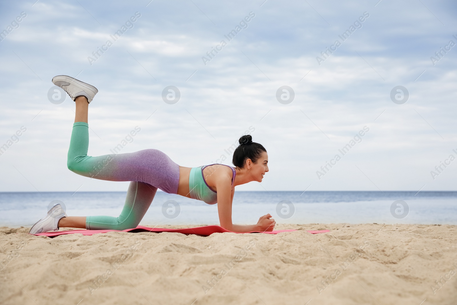 Photo of Young woman doing exercise on beach. Body training