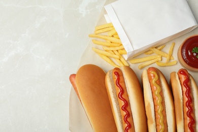 Photo of Composition with hot dogs, french fries and sauce on table, top view. Space for text