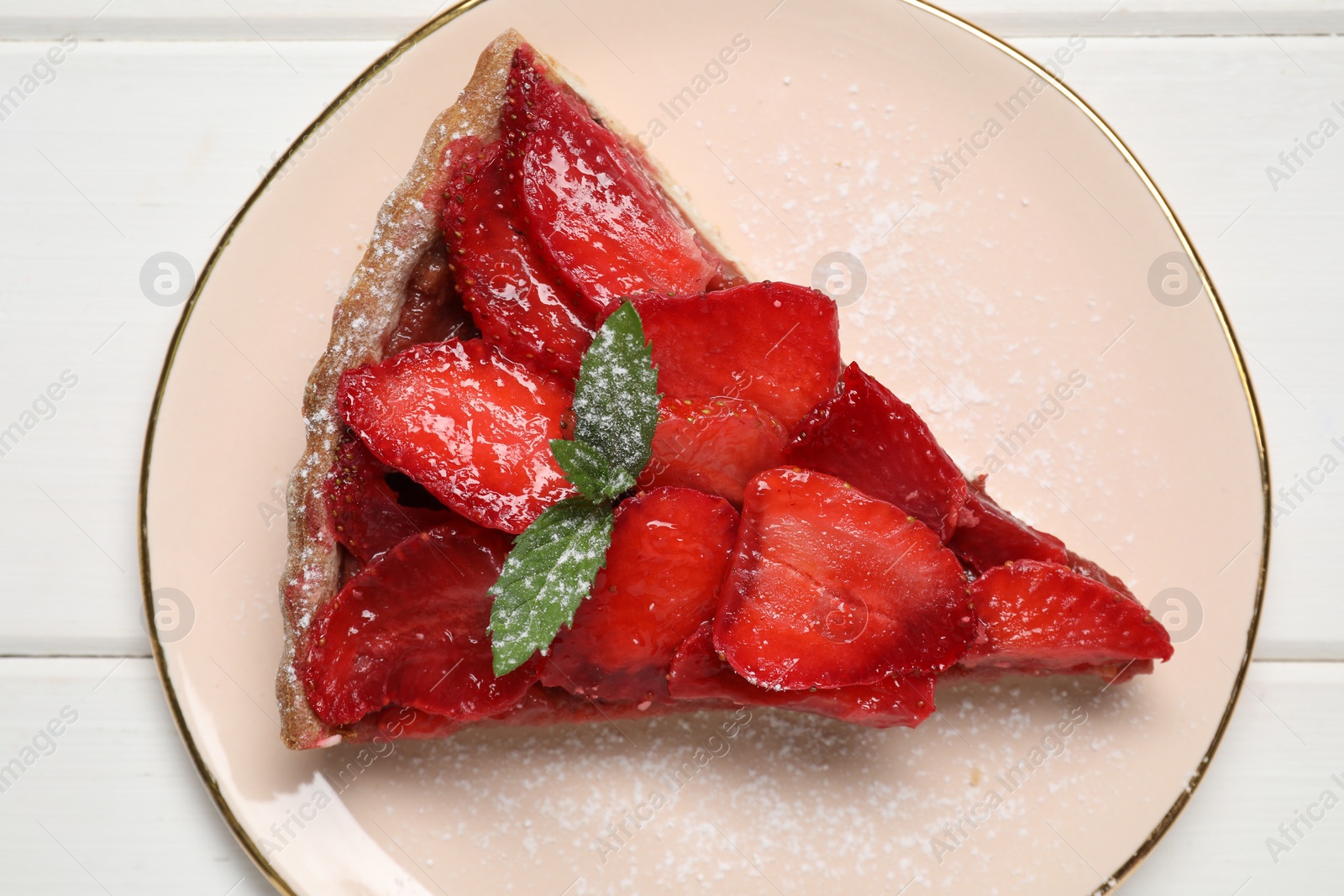 Photo of Piece of delicious strawberry tart with mint on white wooden table, top view