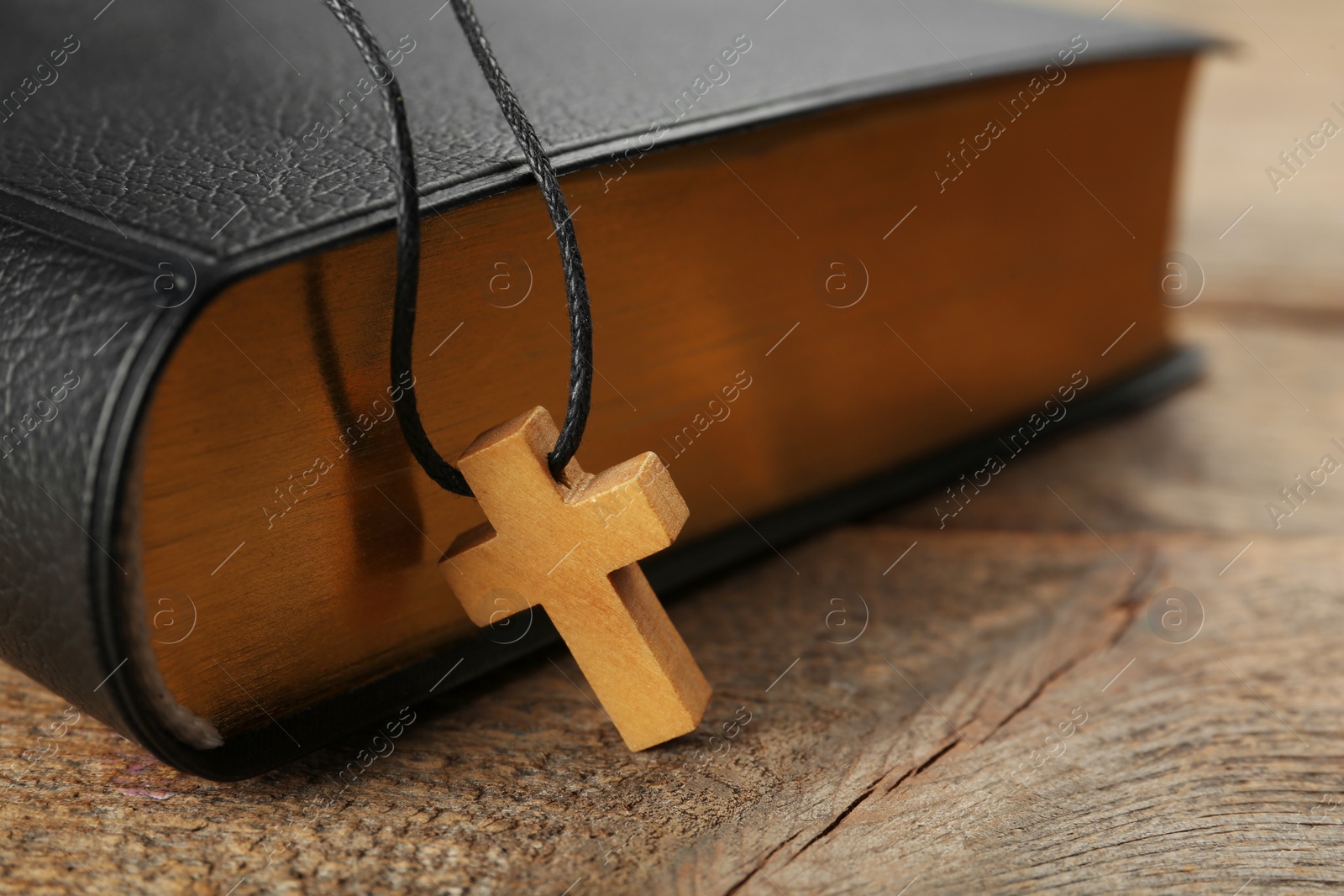 Photo of Christian cross and Bible on wooden table, closeup. Space for text