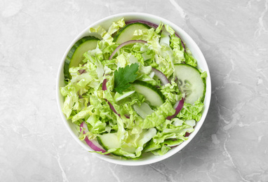 Tasty salad with cabbage and cucumbers on light grey marble table, top view