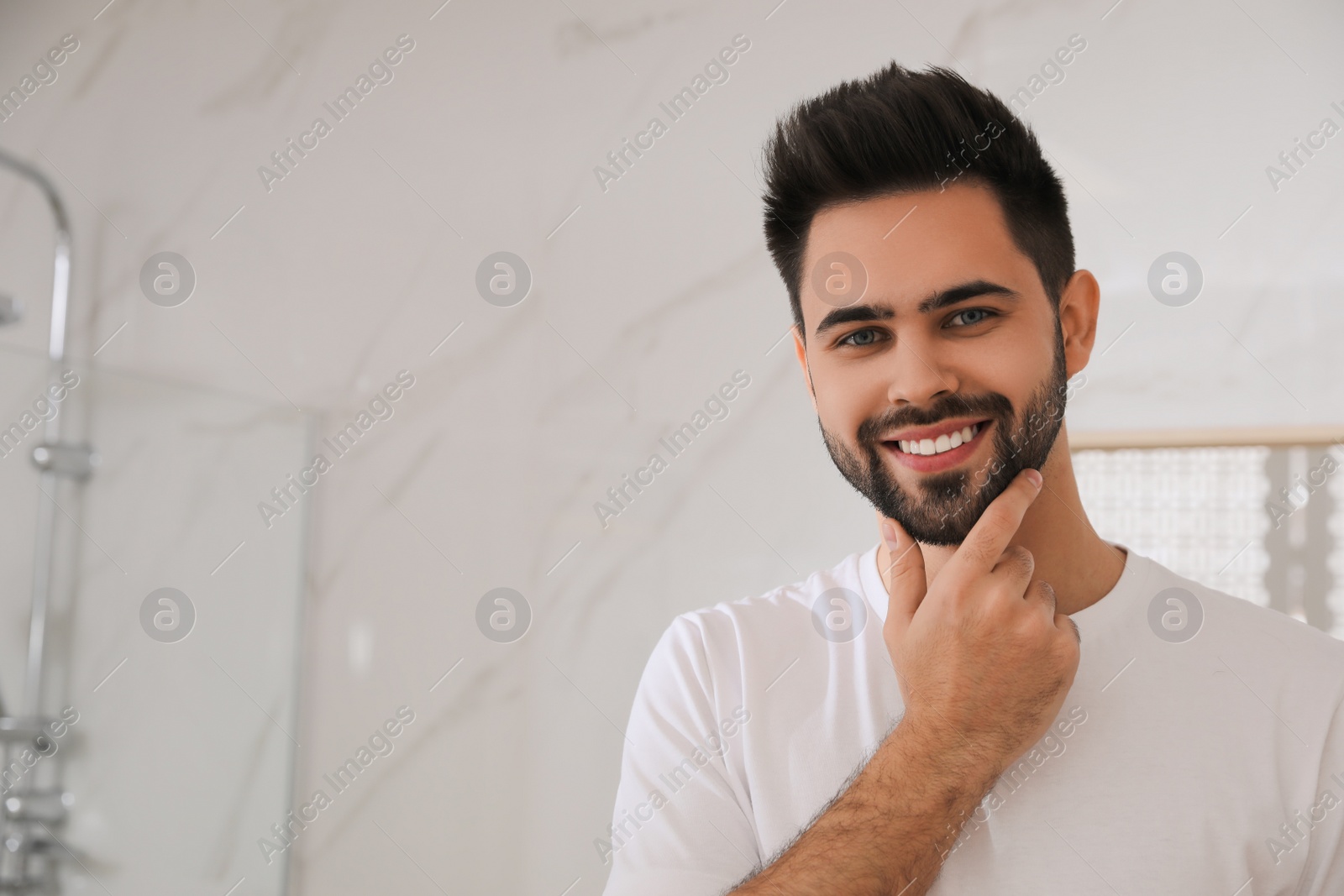 Photo of Handsome young man after shaving in bathroom, space for text