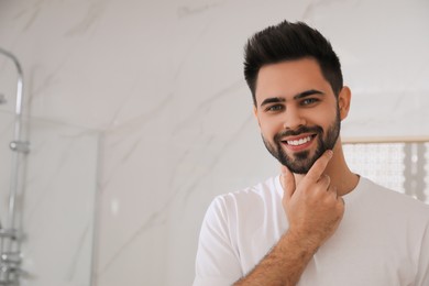 Handsome young man after shaving in bathroom, space for text