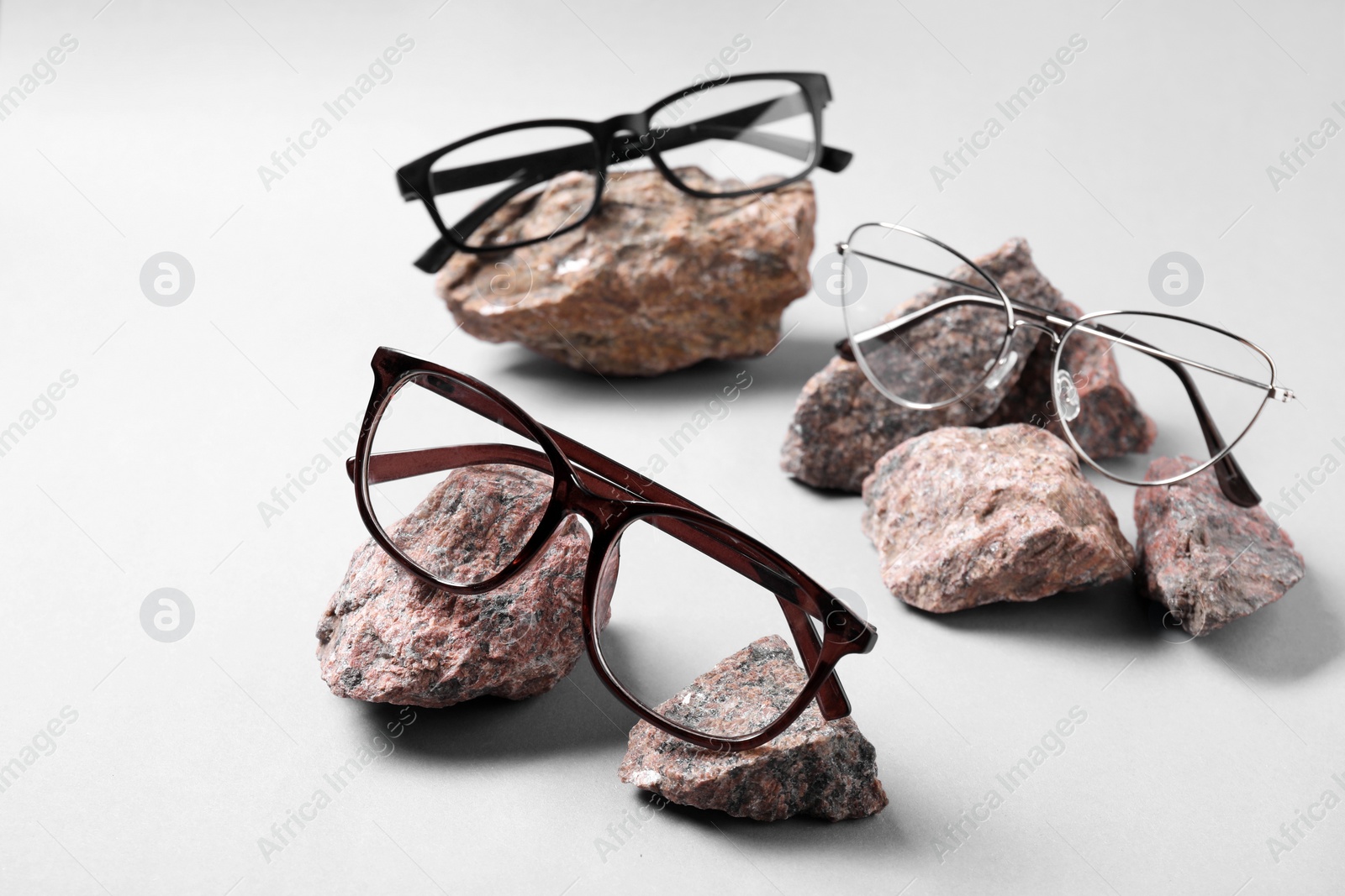 Photo of Different stylish glasses on stones against white background