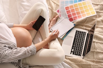Photo of Pregnant woman working on bed at home, above view. Maternity leave
