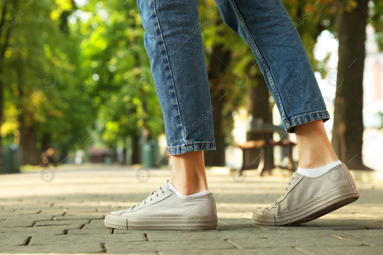 Photo of Woman in stylish sneakers walking on city street, closeup