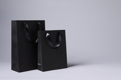 Photo of Black paper bags on light grey background, space for text