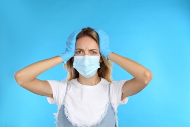 Photo of Stressed woman in protective mask on light blue background. Mental health problems during COVID-19 pandemic