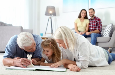 Photo of Mature couple spending time with their granddaughter at home. Happy family