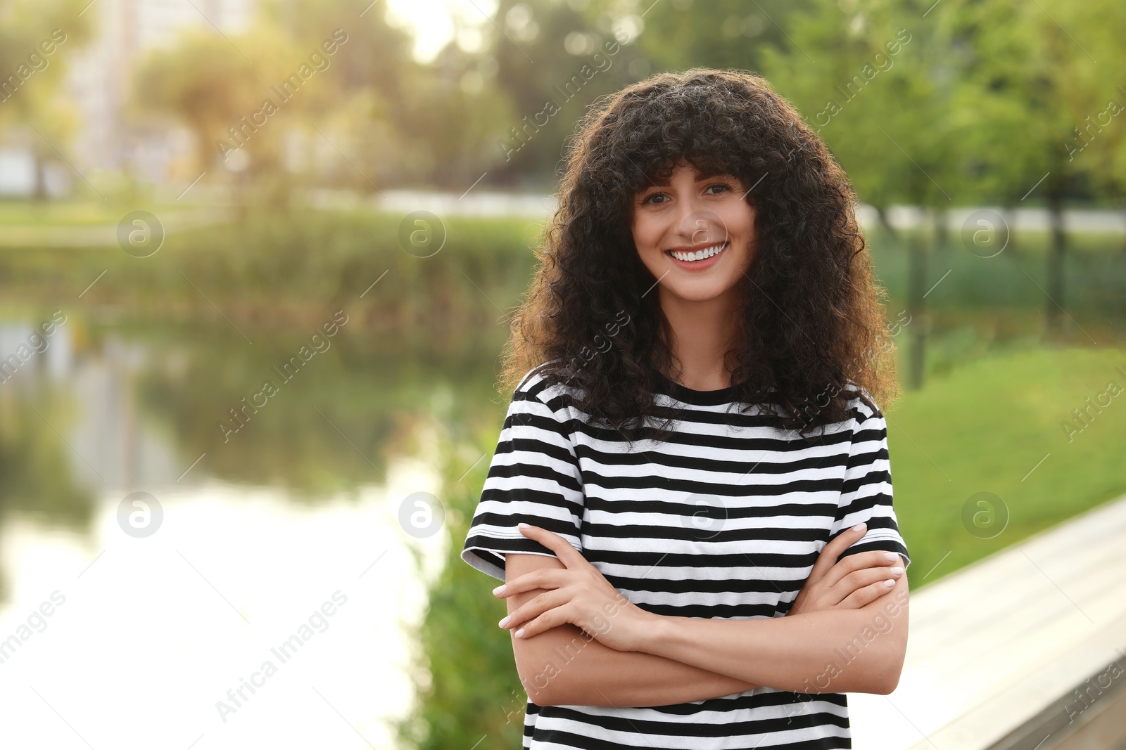 Photo of Portrait of beautiful woman with crossed arms outdoors. Attractive lady smiling and looking into camera. Space for text