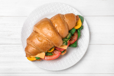 Photo of Tasty vegetarian croissant sandwich on white wooden table, top view